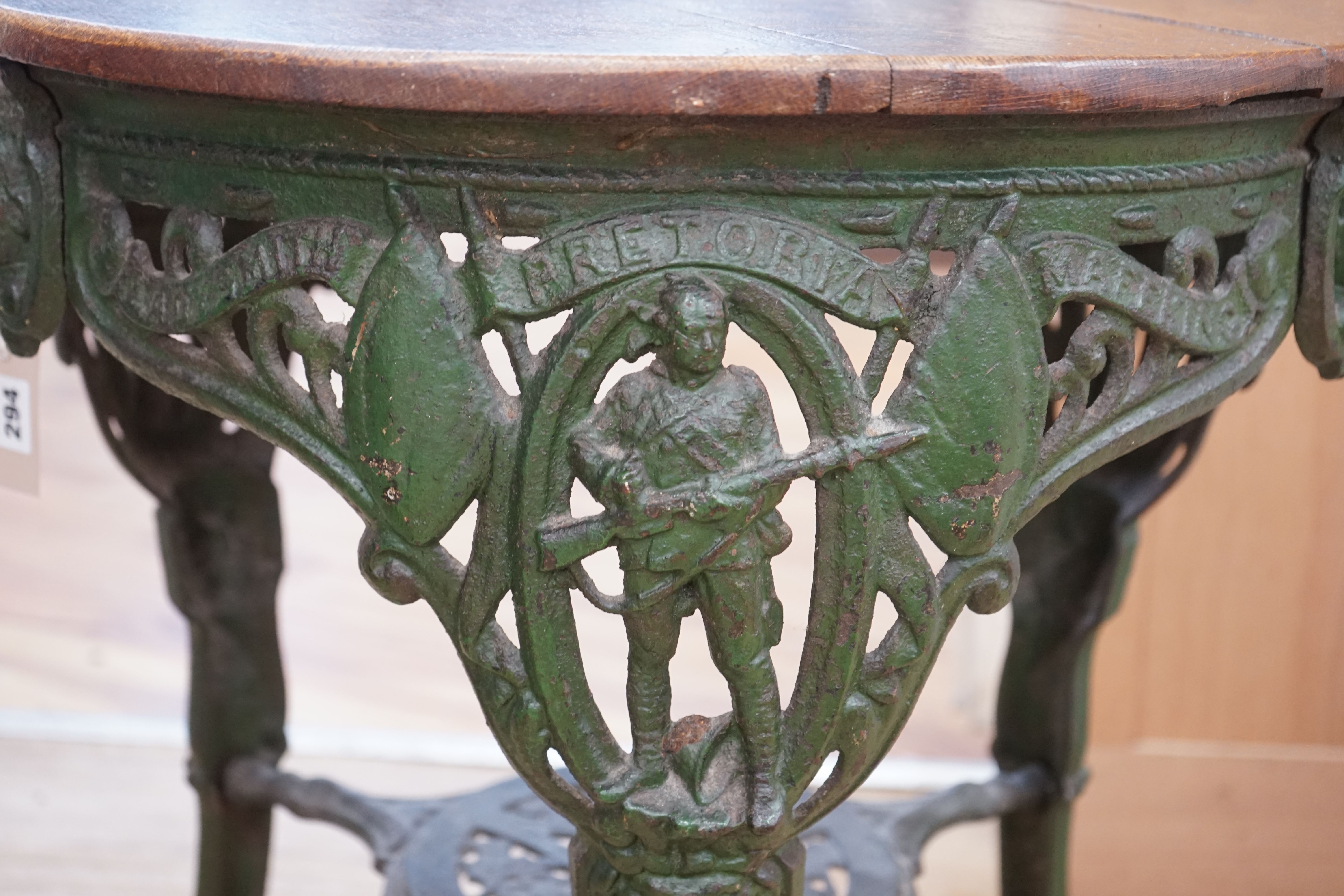 A rare early 20th century Boer War commemorative cast iron pub table, decorated with standing soldiers beneath Ladysmith, Pretoria and Mafeking scrolls, legs bearing registered number 364112, the circular oak top 62cm di